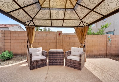 Backyard pergola with cozy seating creates a peaceful outdoor retreat. Perfect for relaxing near the pool in this Casa Grande home.
