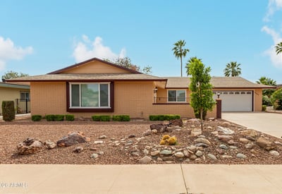 Front exterior with classic desert landscaping and mature greenery. This Sun City property highlights low-maintenance design and updated home features.