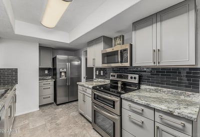 Kitchen featuring stainless steel appliances, updated cabinets, and stylish backsplash. This Sun City home showcases contemporary upgrades and efficient design.