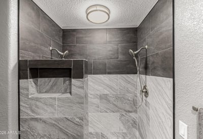 Walk-in shower featuring custom tile surround and built-in shelving. This Sun City home highlights upgraded bathrooms and contemporary style.