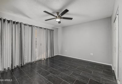 Bright bedroom with tile flooring, ceiling fan, and natural light. This Sun City home offers updated finishes and flexible room options.