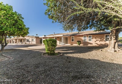 Backyard featuring mature trees offering shade and privacy. This Sun City home includes spacious outdoor areas perfect for relaxation.