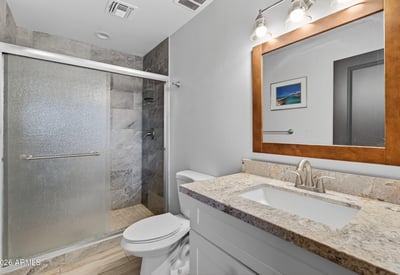 Bathroom with granite vanity, modern fixtures, and tiled shower, offering both style and practicality.