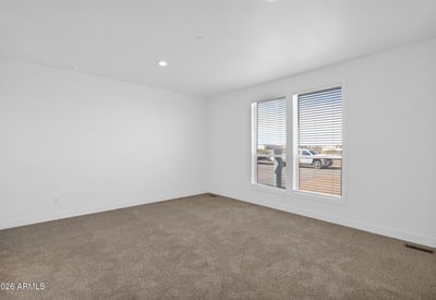 Comfortable primary suite offering generous dimensions, soft carpeting, and large windows that welcome natural light. A relaxing space designed for rest while enjoying peaceful desert surroundings.