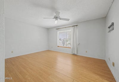 This spacious primary suite features neutral finishes, durable flooring, and abundant natural light. The flexible floorplan allows for comfortable furnishings while creating a peaceful retreat within the home.
