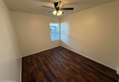 Comfortable bedroom featuring wood-look flooring, ceiling fan, and natural light. The spacious layout provides a relaxing retreat while accommodating a variety of furniture configurations.