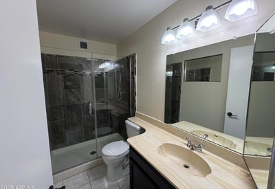 Beautifully upgraded primary bathroom highlighted by a custom tile walk-in shower with glass enclosure, modern lighting, and extended vanity space. Quality updates create a spa-inspired atmosphere.
