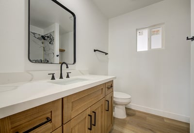 Enjoy modern design with a spacious quartz vanity, custom cabinetry, updated lighting, matte black fixtures, and quality finishes throughout this remodeled bathroom.