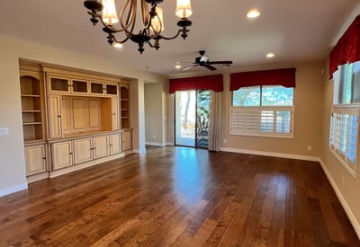 Expansive living room featuring custom built-in cabinetry, upgraded wood floors, elegant chandelier, recessed lighting, and abundant natural light. A warm and inviting gathering space designed for comfortable everyday living.