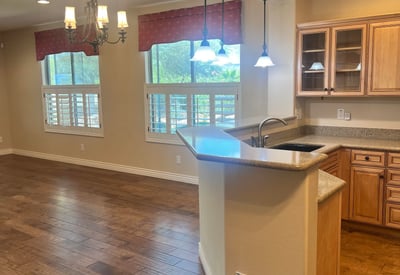 Inviting open-concept kitchen and dining area with custom cabinetry, breakfast bar, pendant lighting, plantation shutters, and upgraded flooring that creates a bright, welcoming atmosphere perfect for entertaining.