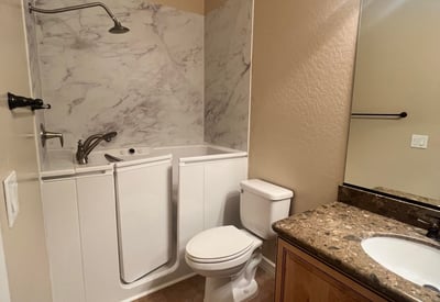 Well-appointed guest bathroom featuring a convenient walk-in tub, updated vanity, durable tile flooring, and attractive finishes that provide comfort, accessibility, and everyday functionality.