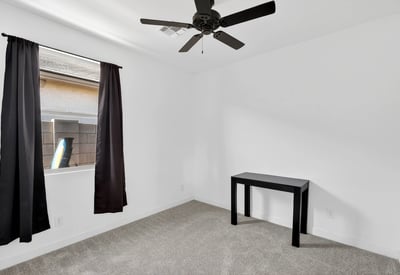 A welcoming secondary bedroom featuring plush carpeting, ceiling fan, natural light, and flexible space for guests, family members, or everyday living.