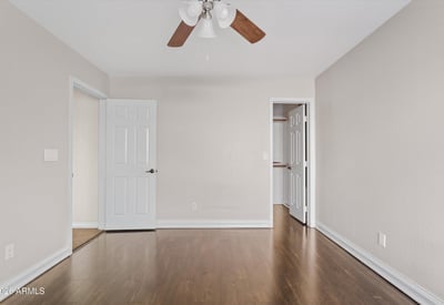 This spacious bedroom offers attractive wood flooring, neutral finishes, ceiling fan, and convenient access to nearby storage. A flexible room that adapts to your needs.