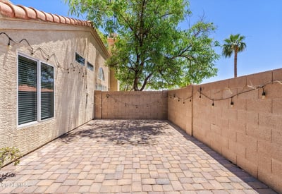 The spacious paver patio offers additional outdoor living space ideal for grilling, outdoor dining, or creating a peaceful sitting area. Mature landscaping adds shade and privacy to this Chandler backyard.
