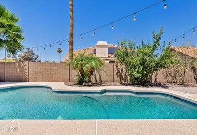 The beautifully maintained backyard features a sparkling pool, mature landscaping, decorative lighting, and privacy, creating an ideal outdoor retreat for everyday enjoyment.