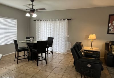 Dining area with large windows, tile flooring, ceiling fan, and convenient access to the covered patio creates a bright and comfortable setting for everyday dining.