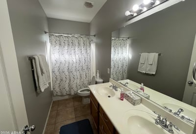 Full bathroom showcasing a spacious dual-sink vanity, large mirror, and tub/shower combination, providing practical convenience for family members and guests.