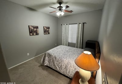 Secondary bedroom with neutral d cor, ceiling fan, and ample floor space, offering flexibility for guests, a home office, or a hobby room.