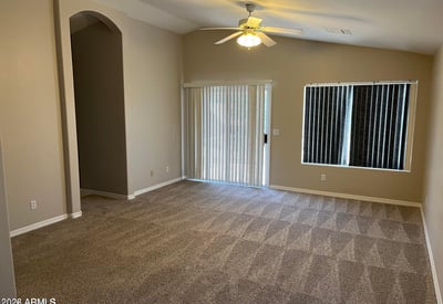 This oversized primary bedroom offers plush carpeting, a ceiling fan, abundant natural light, and generous space for a sitting area, creating a comfortable private retreat.
