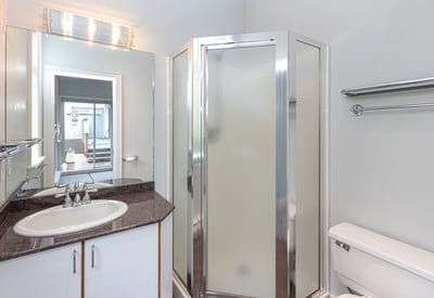 Modern bathroom featuring a glass shower, sleek countertops, and ample storage for convenience and functionality.