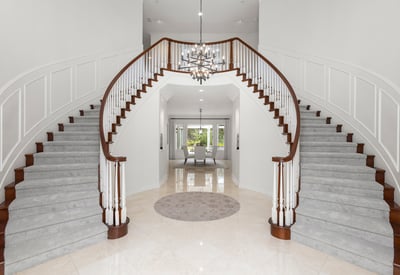 Grand foyer with dual staircases and a modern chandelier, creating an impressive first impression.