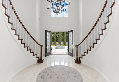 Welcome to this striking foyer featuring a grand staircase and inviting double front doors that open to scenic views.