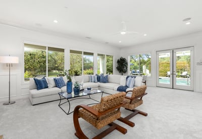 Spacious living area with large windows, offering abundant natural light and direct views of the pool.