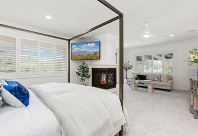 Primary Bedroom -Spacious bedroom with a cozy fireplace, adjacent sitting area, and abundant natural light throughout. (TV Included)