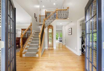 Bright and inviting entryway featuring a spacious layout, hardwood floors, and a sweeping staircase.