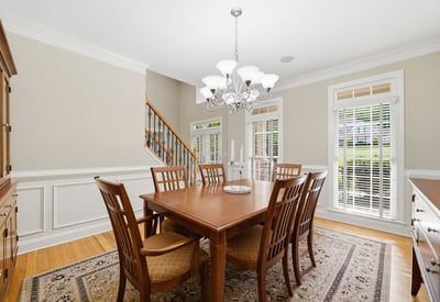 Bright dining room with tall windows, transom detail, plantation shutters, and beautiful trim work a polished space that feels connected to the main level while still having its own sense of occasion.