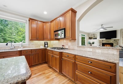 This spacious kitchen features rich cabinetry, granite countertops, and ample natural light, perfect for culinary enthusiasts.
