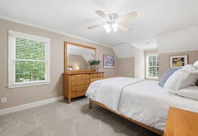 Bright and airy bedroom featuring natural light, modern ceiling fan, and ample storage in a cozy setting.