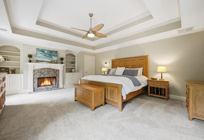 This spacious master bedroom features vaulted ceilings, a cozy fireplace, and ample built-in storage solutions.