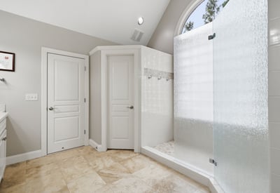 Modern bathroom featuring a spacious walk-in shower with frosted glass and natural light.