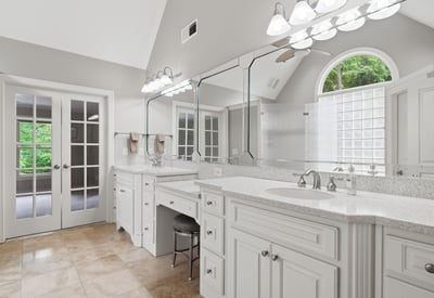 Spacious bathroom featuring dual vanities, abundant natural light, and access to a private outdoor space.