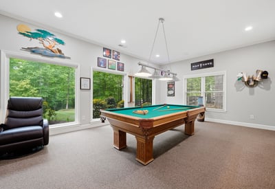 Spacious game room featuring a billiards table and large windows that invite natural light.