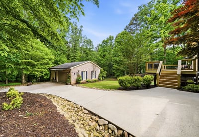 Spacious home nestled on a lush lot, featuring ample outdoor living space and a welcoming driveway.