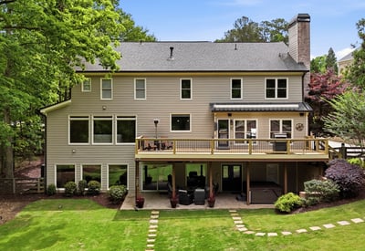 Spacious home with expansive outdoor deck, large windows, and a beautifully landscaped backyard ideal for gatherings.