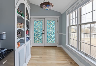 Bright and inviting sunroom with unique stained glass doors and built-in shelving for added character.