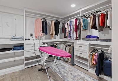 Spacious walk-in closet equipped with ample storage and a convenient ironing station for modern living.