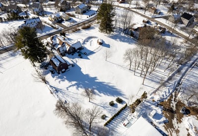 Expansive winter landscape featuring a well-positioned home surrounded by snowy grounds and scenic neighborhood views.
