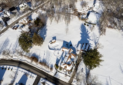 Stunning aerial view of a winter landscape featuring a spacious property amidst a pristine snowy backdrop.