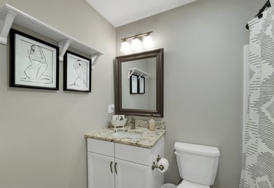Modern bathroom featuring a granite countertop, sleek fixtures, and contemporary artwork for added character.