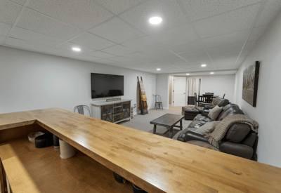 Spacious, versatile finished basement featuring a cozy lounge area and a convenient bar for entertaining.