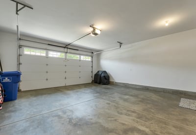 Spacious garage with ample storage potential, featuring a large door and well-lit interior.