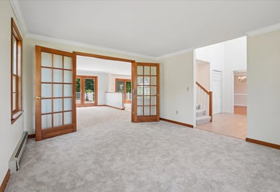 Spacious living area with abundant natural light, featuring dual French doors for flexible entertaining options.