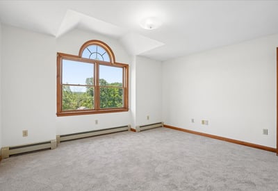 Bright and airy room featuring large windows and plush carpet, perfect for creative space or cozy retreat.