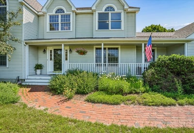 Spacious front porch with landscaped garden offers inviting outdoor space for relaxation and gatherings.