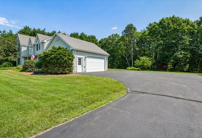 This spacious home features a circular driveway and lush landscaping, perfect for outdoor gatherings and privacy.