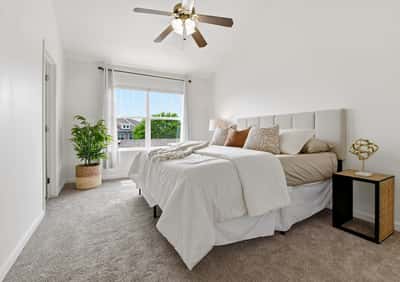 Bright and spacious primary bedroom featuring large window, plush brand new carpeting, and modern ceiling fan for comfort.